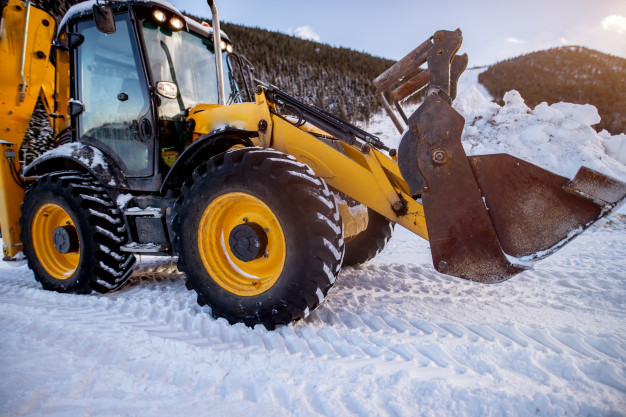Traktorbager odpratáva sneh z parkoviska poča zimnej údržby | STAVMAXBB